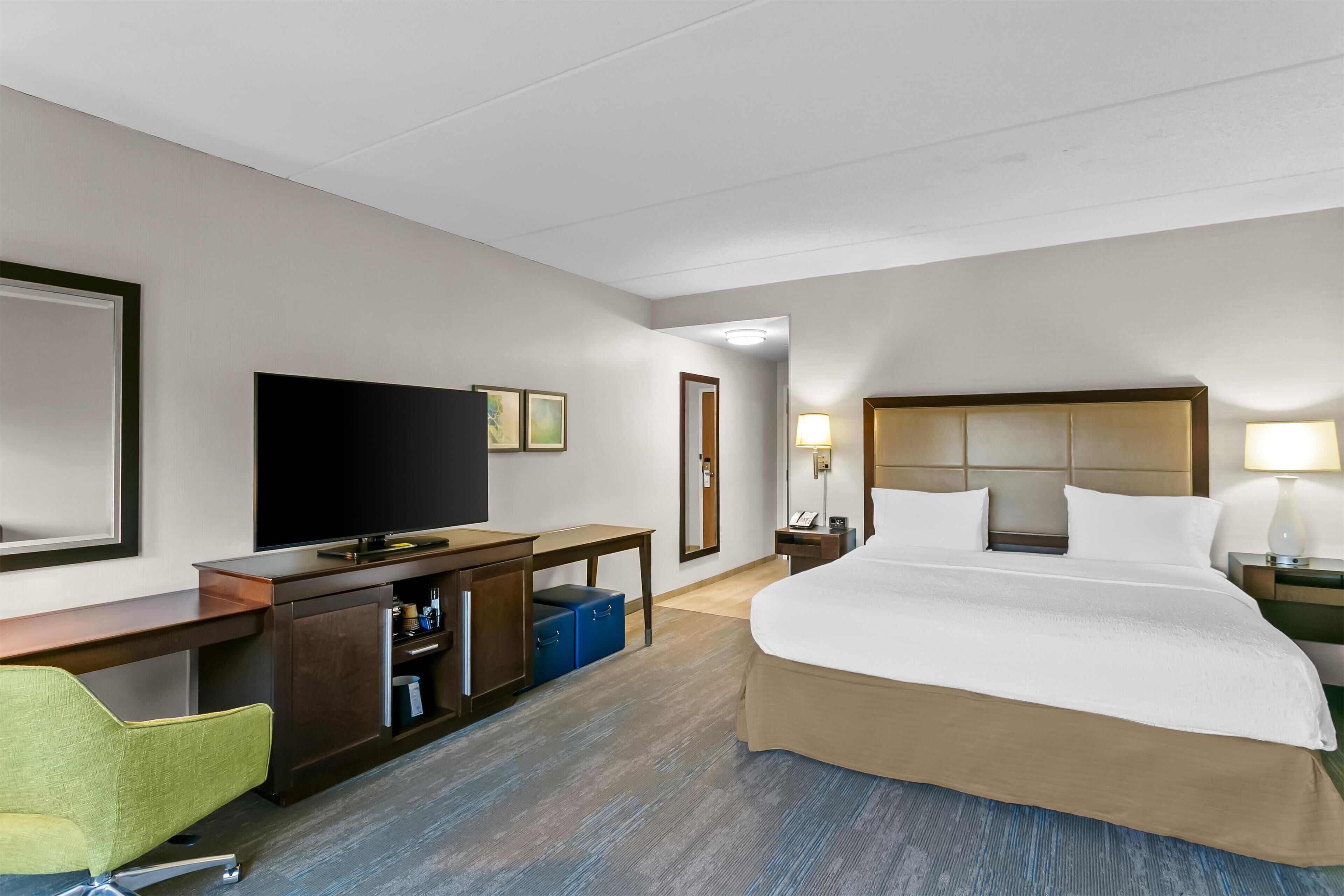 A hotel room with a bed, a desk, a television, and a chair.