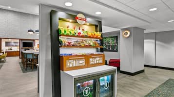 A snack bar with a variety of snacks and beverages, a seating area with chairs and a table, and a television in the background.