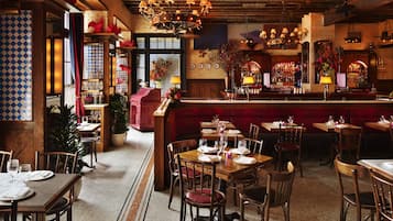 A restaurant interior with wooden tables, chairs, a bar area, and a patterned floor.