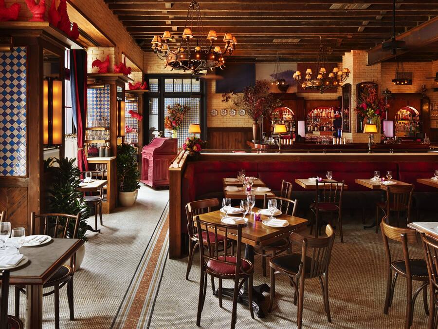 A restaurant interior with wooden tables, chairs, a bar area, and a patterned floor.
