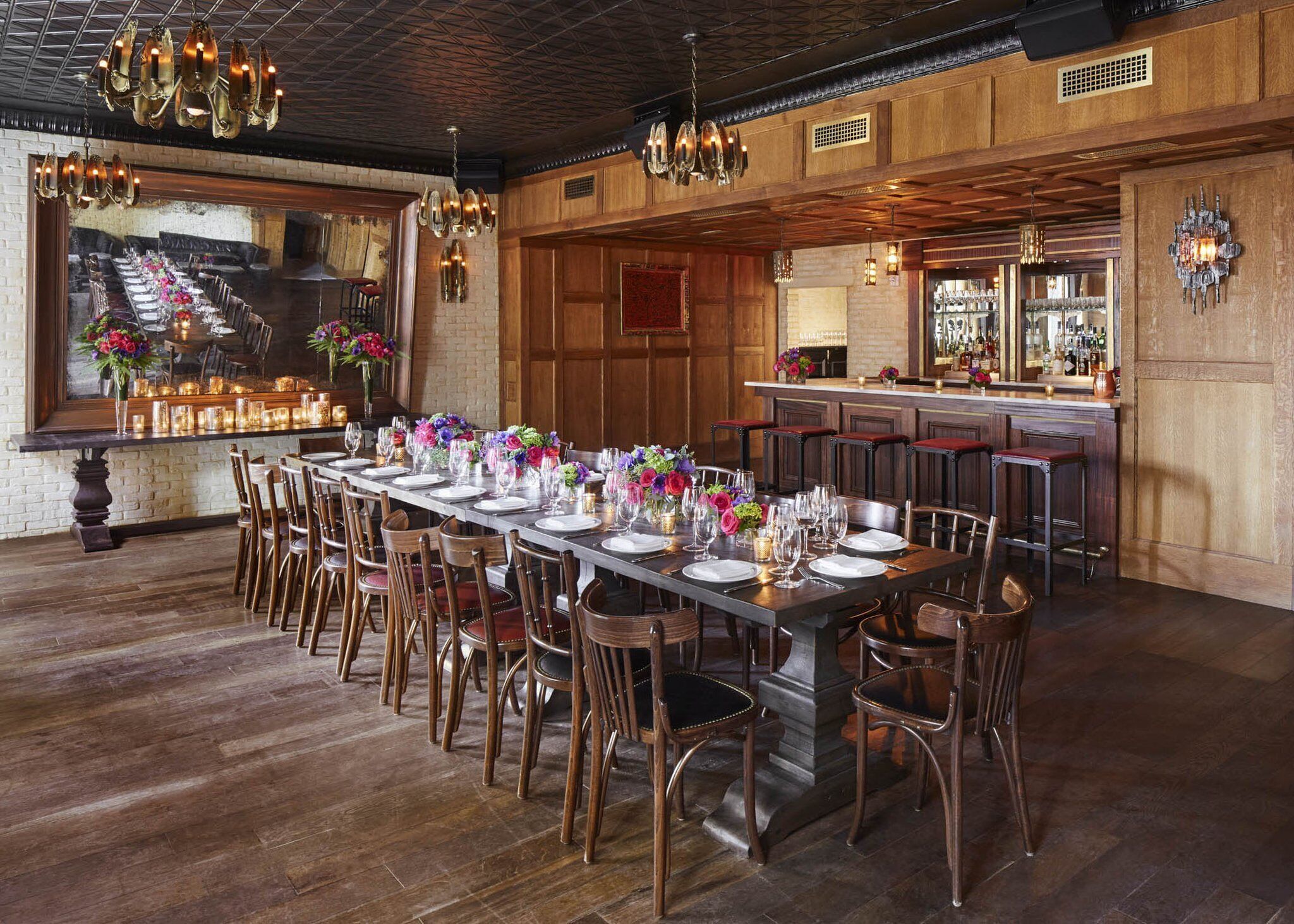 A long dining table set with chairs, a bar area, and a view of a staircase.