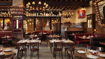 A restaurant interior with wooden tables, booths, and a brick wall.