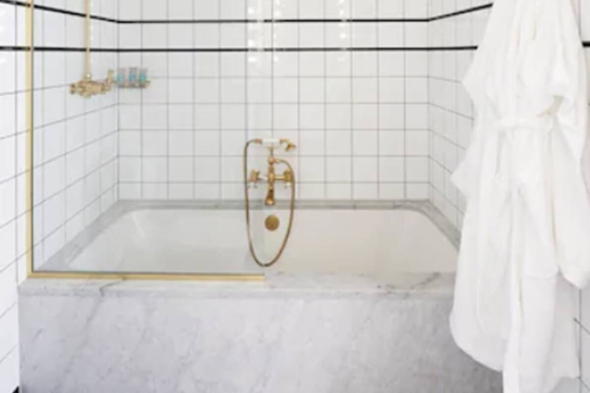 Un baño moderno con ducha de vidrio, paredes de azulejos blancos y suelo de mármol.