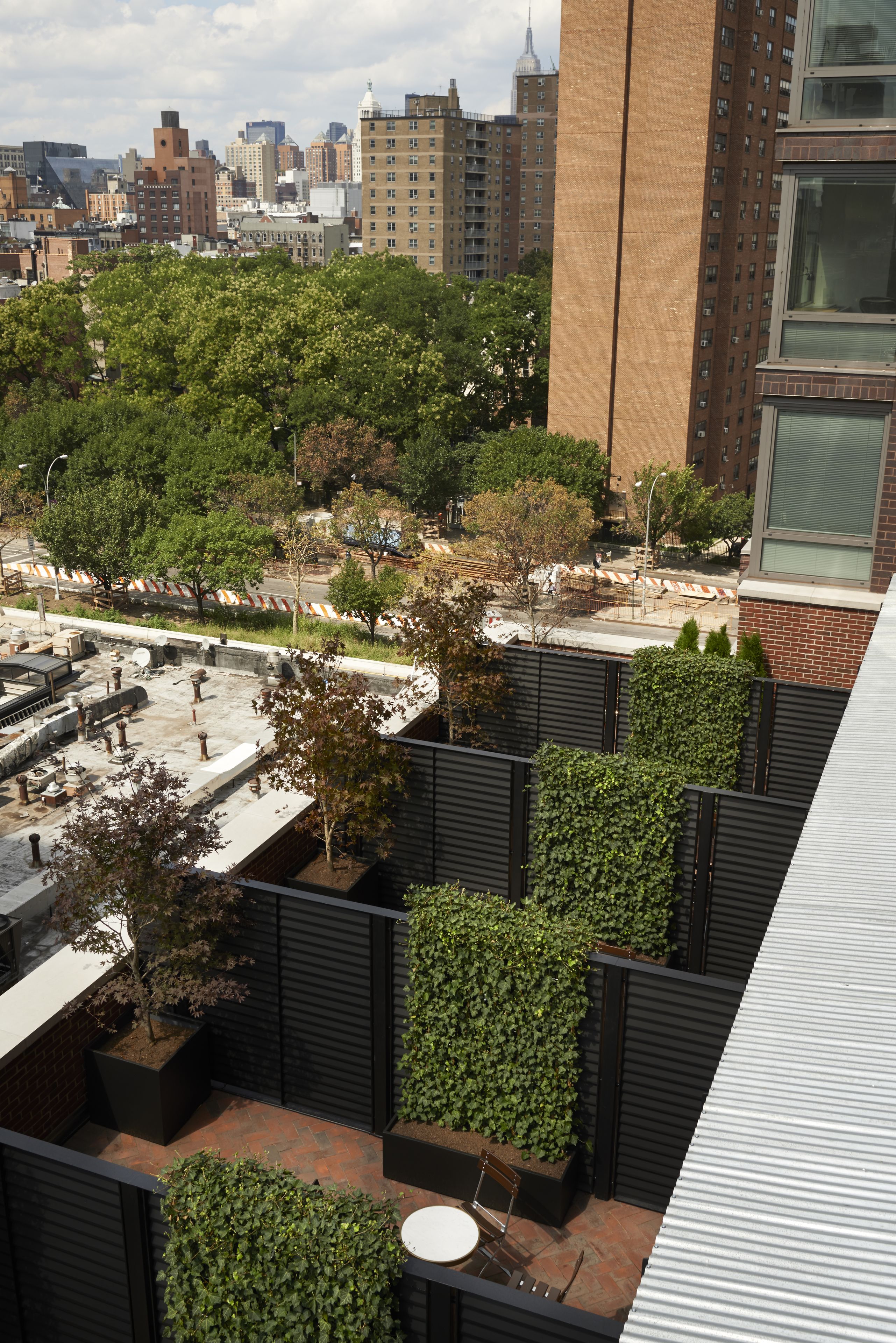 Un jardín en la azotea con plantas en macetas y una zona de estar.