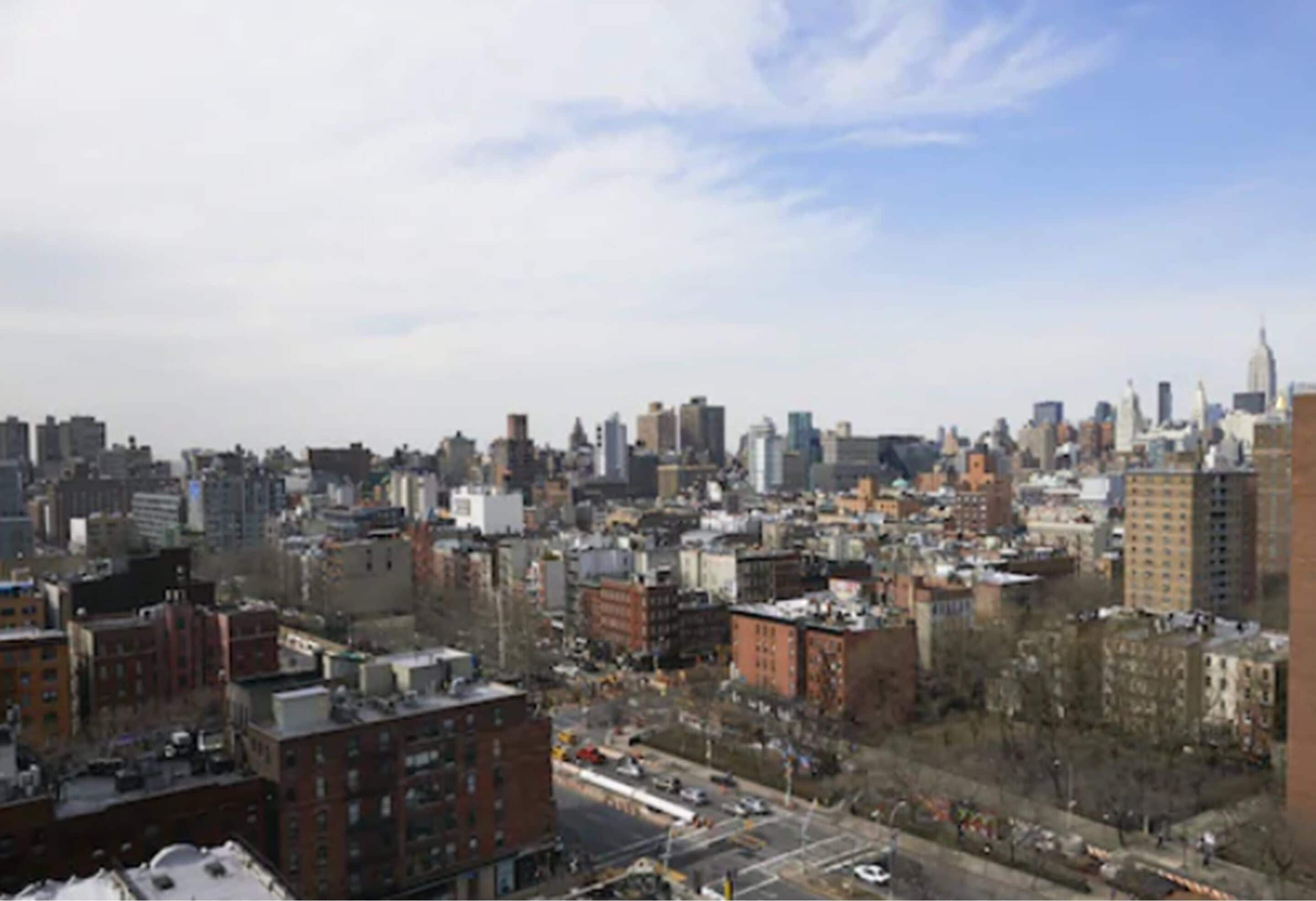A cityscape with dense urban buildings, a mix of high and low-rise structures, and a clear sky.