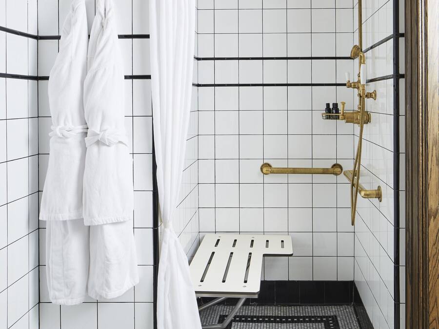 A bathroom with a shower, a bench, and a towel rack.