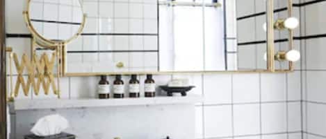 A bathroom with a large mirror, vanity, and a sink.