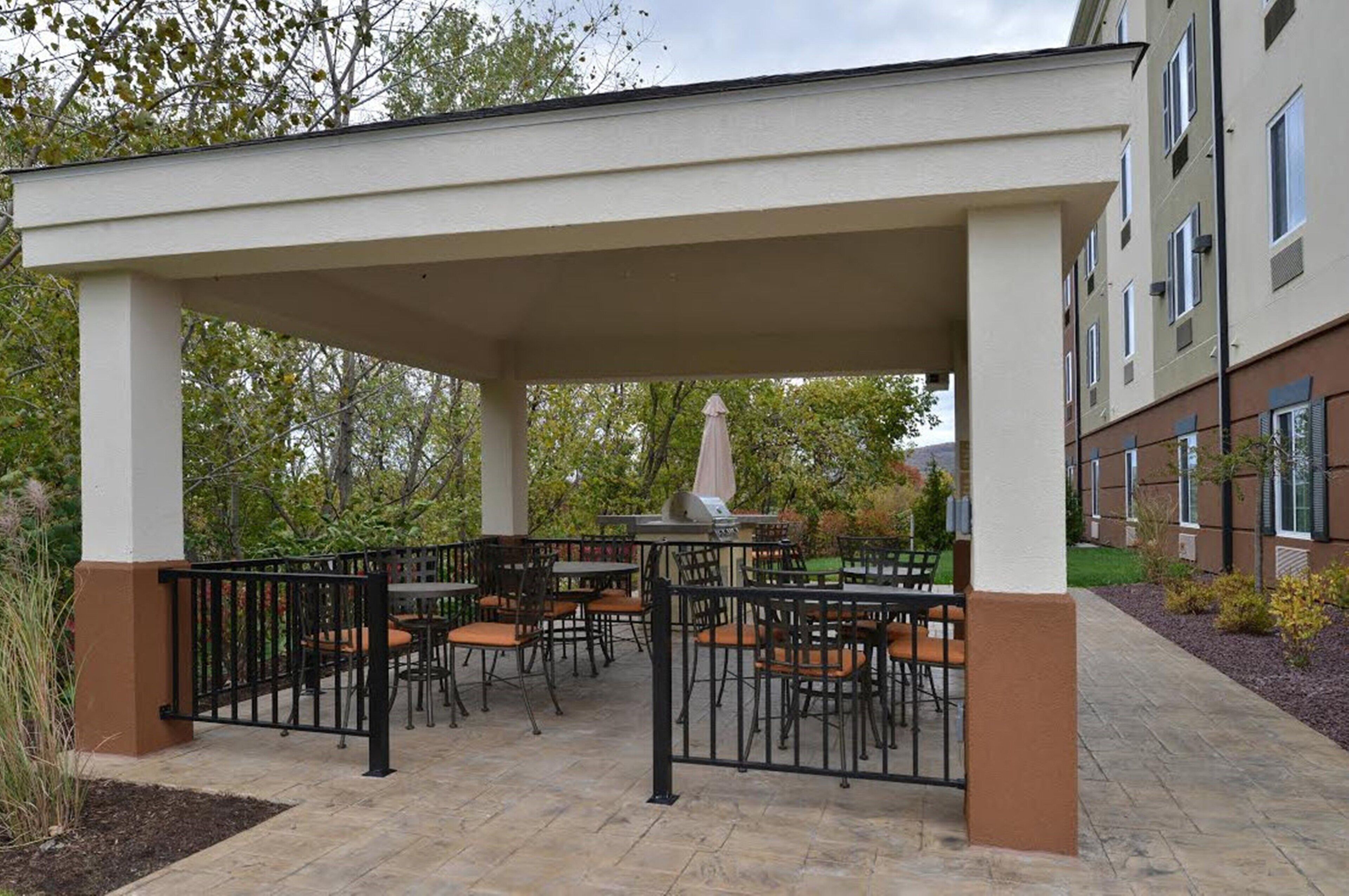 An outdoor patio with tables and chairs, a statue, and a building in the background.