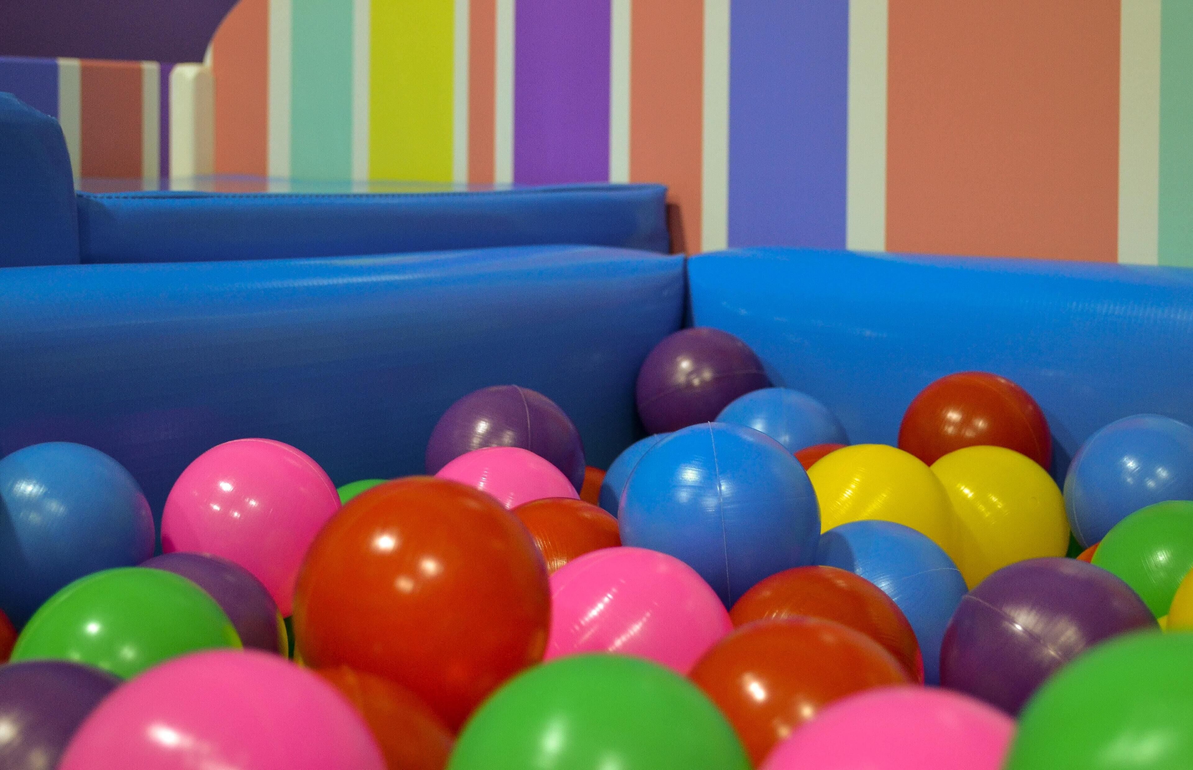 A colorful play area with a blue padded structure and multicolored balls.
