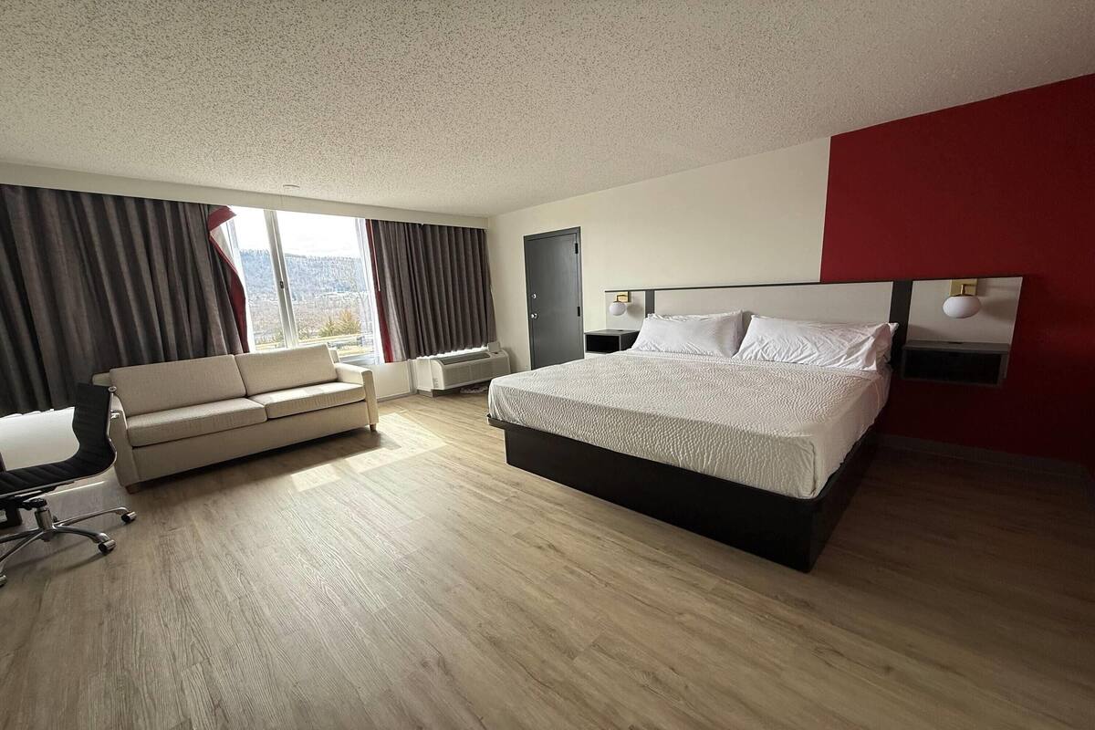 Ett hotellrum med en säng, en soffa, ett skrivbord och utsikt över omgivningarna.