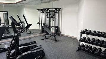 Una palestra con tapis roulant, una panca, una rack per squat e manubri.