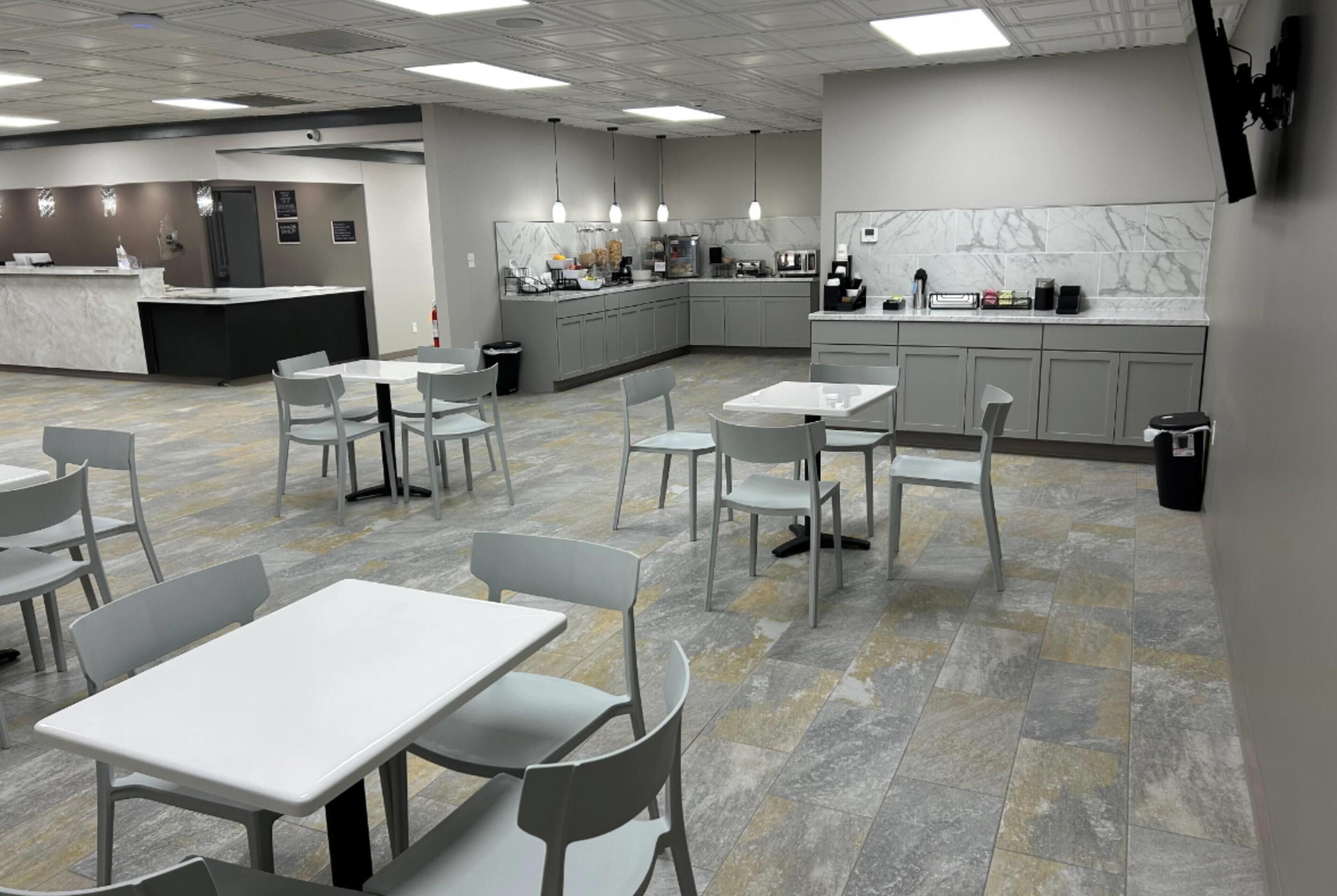 A modern kitchen with marble countertops, a central island, and pendant lighting.
