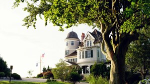 A large, two-story house with a prominent tower and a wrap-around porch. - Castle Hill Inn (Newport)