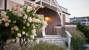 A house with a wooden exterior, a porch with steps, and a white fence. - Castle Hill Inn (Newport)