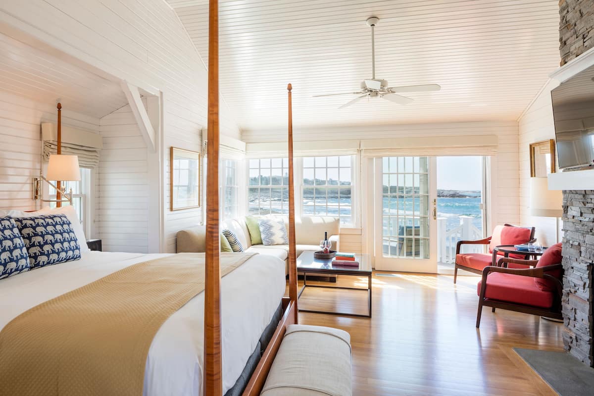 A spacious bedroom with a large bed, a sitting area with a coffee table, and a view of the ocean.