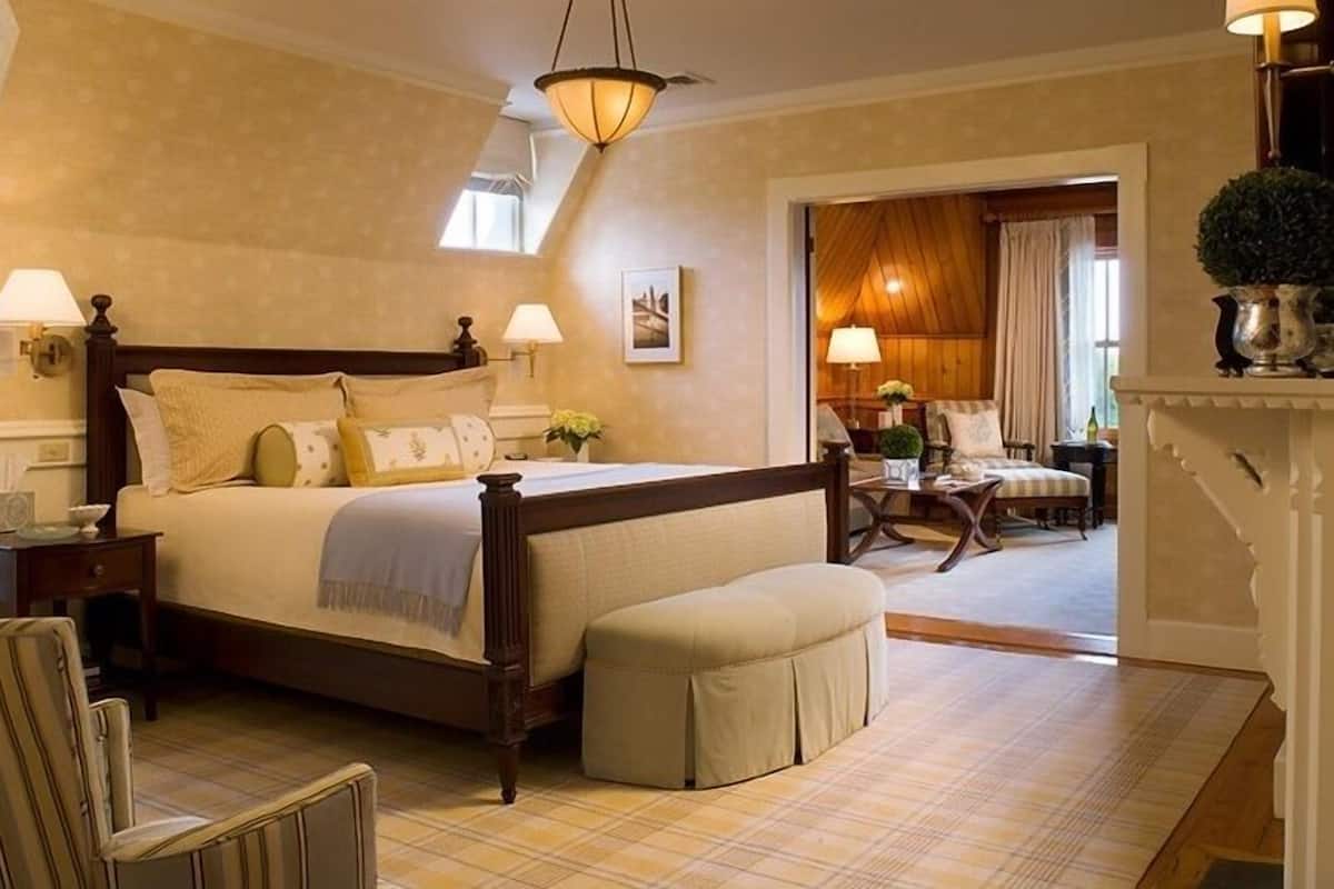 A bedroom with a large bed, bedside tables, a chair, and a small table with a lamp.