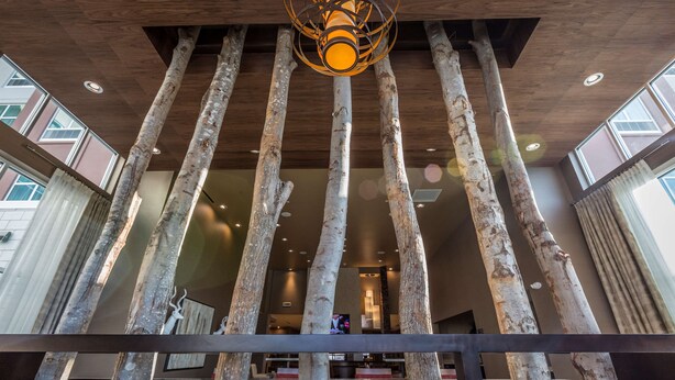 A modern interior with a unique wooden column structure, a central hanging light fixture, and a view of the lobby area. - Homewood Suites by Hilton Charlotte Ballantyne, NC (Charlotte)