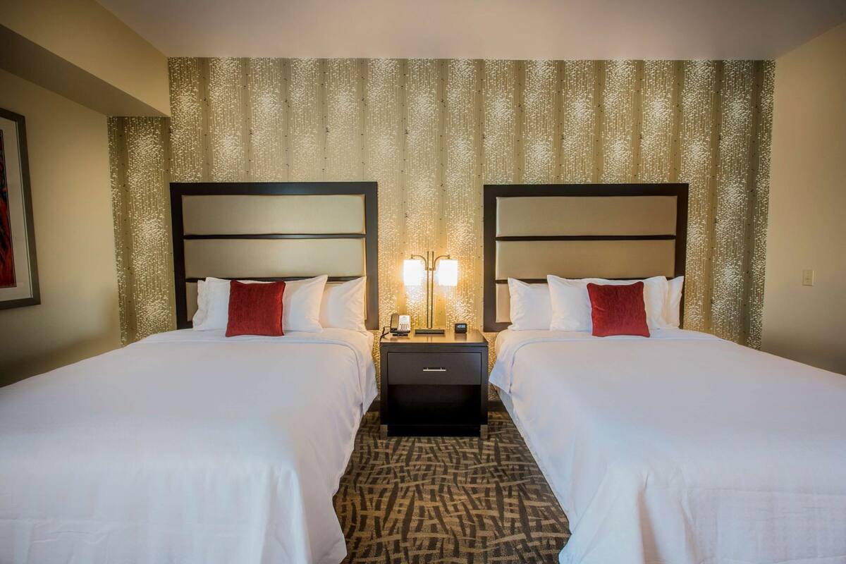 Ein Hotelzimmer mit zwei Betten, einem Nachttisch und einem gemusterten Teppich.