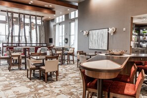 A modern hotel lobby with a central bar area, multiple seating arrangements, and large windows providing natural light. - Homewood Suites by Hilton Charlotte Ballantyne, NC (Charlotte)