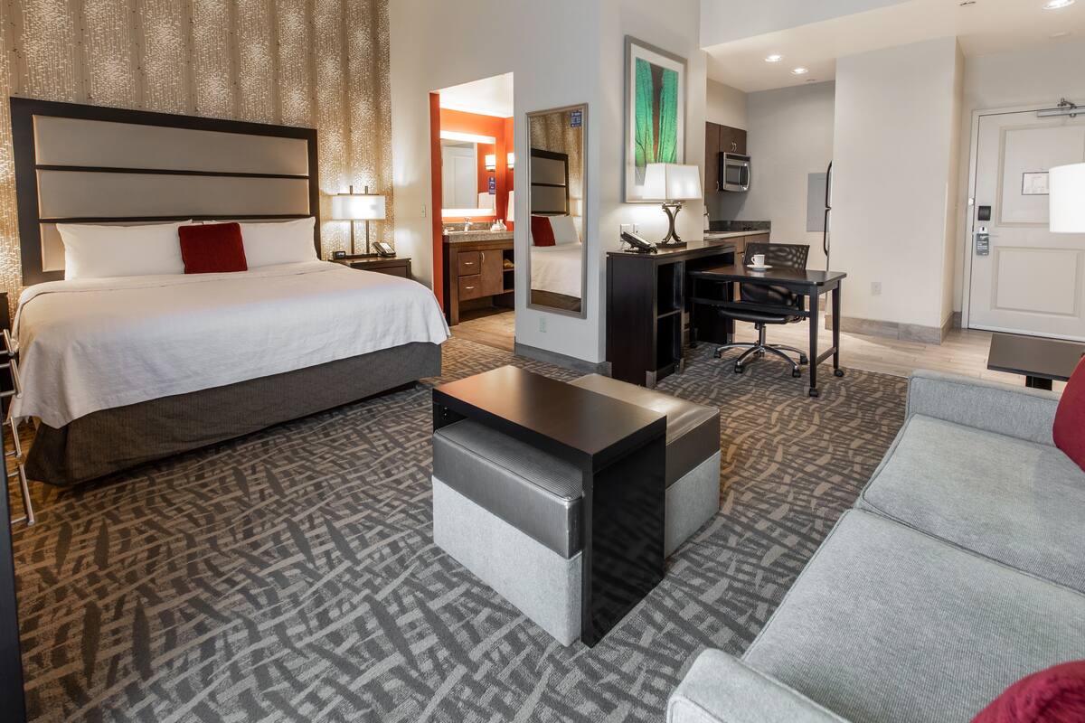 Ein Hotelzimmer mit einem großen Bett, einem Schreibtisch, einer Couch und einem kleinen Couchtisch.