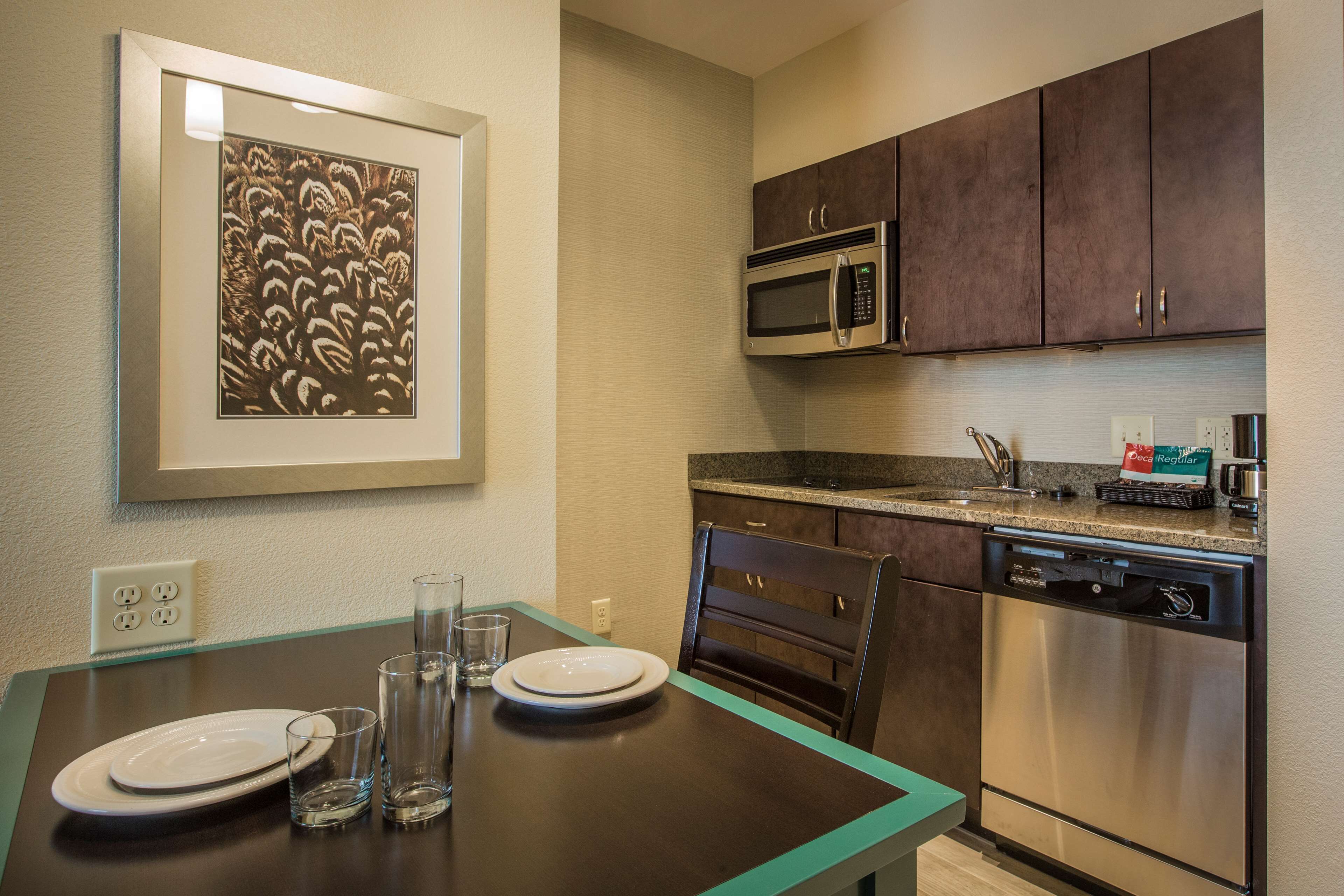 A kitchen with a microwave, dishwasher, and a framed picture on the wall.