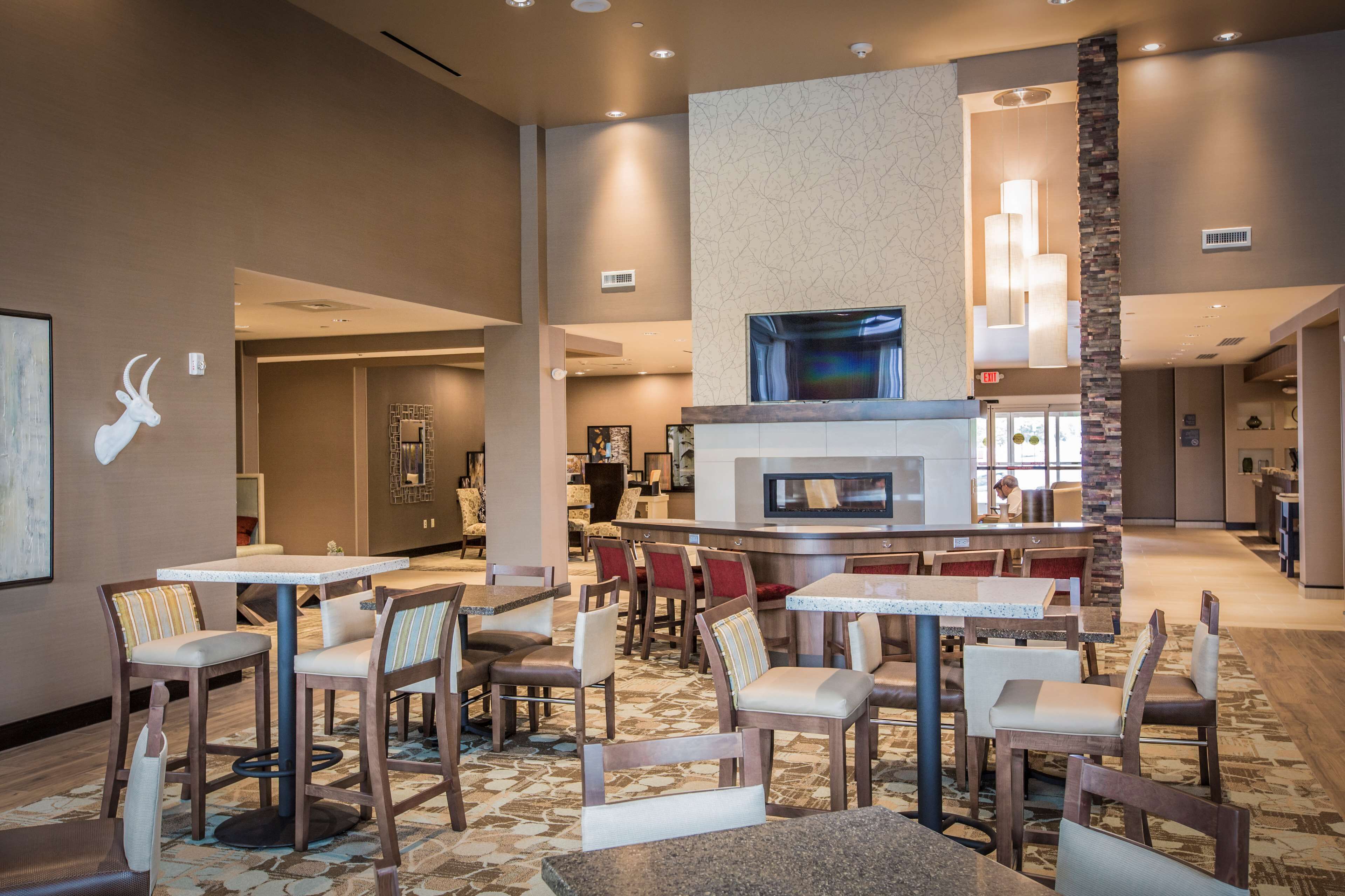Un hall de hotel con una zona de bar central, asientos y una chimenea.