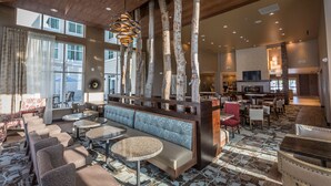 A spacious lobby with a high ceiling, wooden beams, and a seating area with sofas and round tables. - Homewood Suites by Hilton Charlotte Ballantyne, NC (Charlotte)