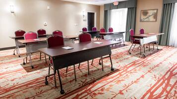 A conference room with multiple tables and chairs, carpeted floor, and a painting on the wall.