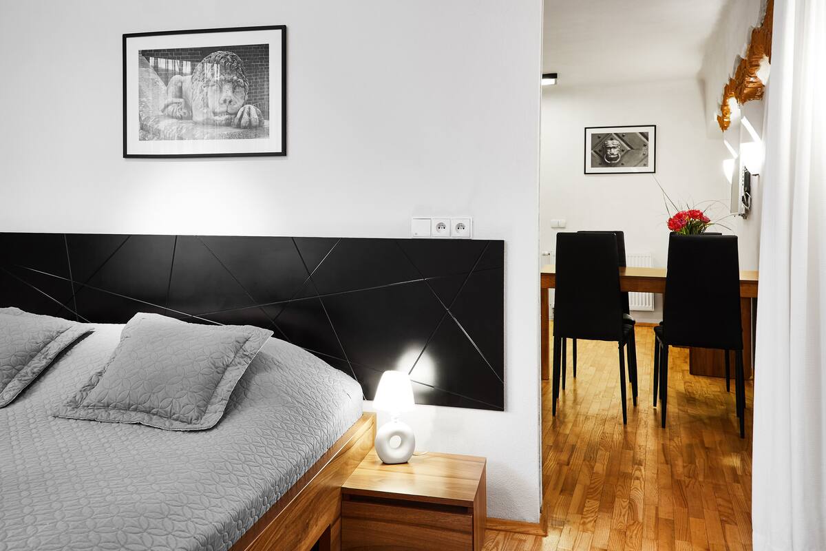A modern bedroom with a bed, bedside table, and a wall-mounted lamp.
