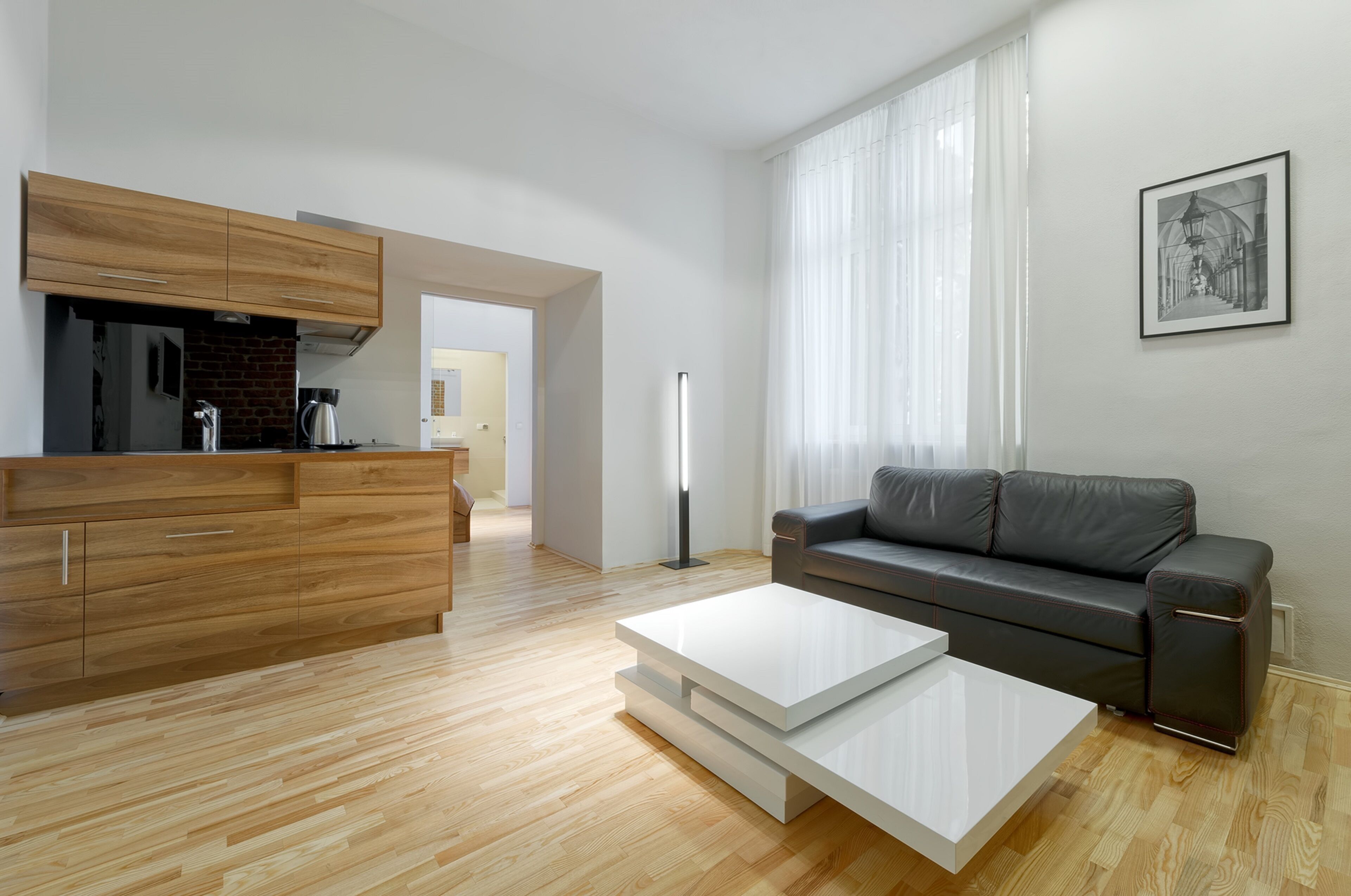 Un salon moderne comprenant un canapé, une table basse et un coin cuisine avec des meubles en bois et un mur de fond en briques.