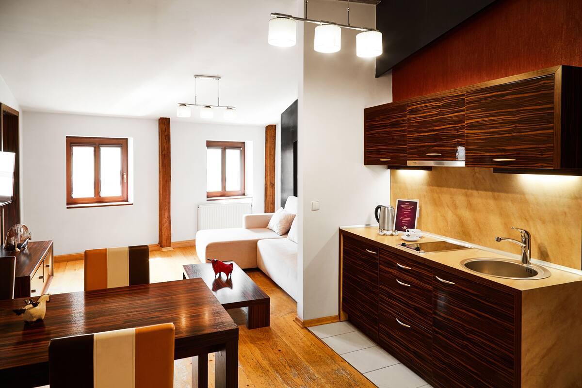 A modern kitchen with wooden cabinets, a built-in sink, and a dining area with a wooden table and chairs.