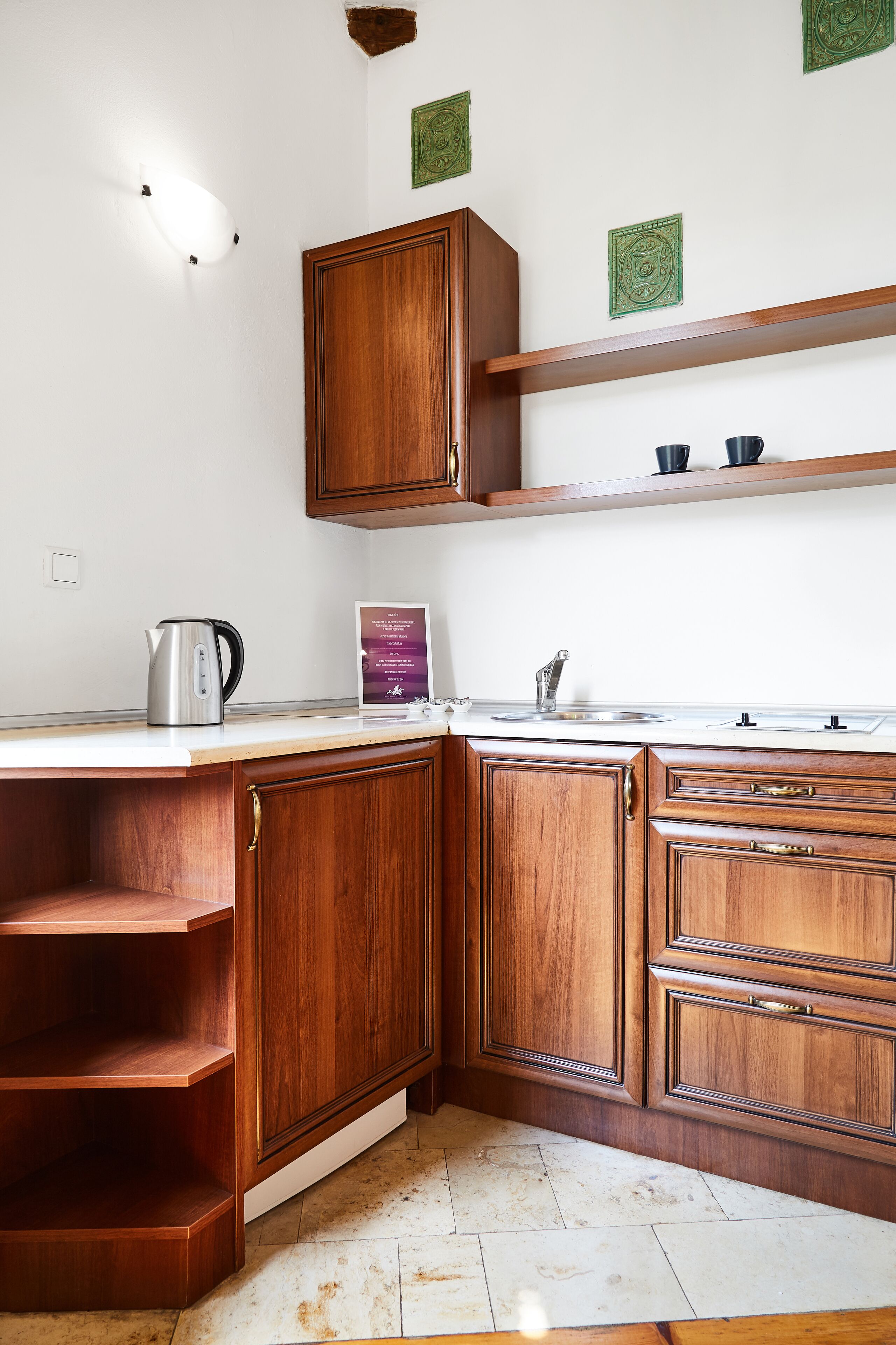 Une cuisine avec des meubles de rangement en bois, un plan de travail, une bouilloire et un panneau.