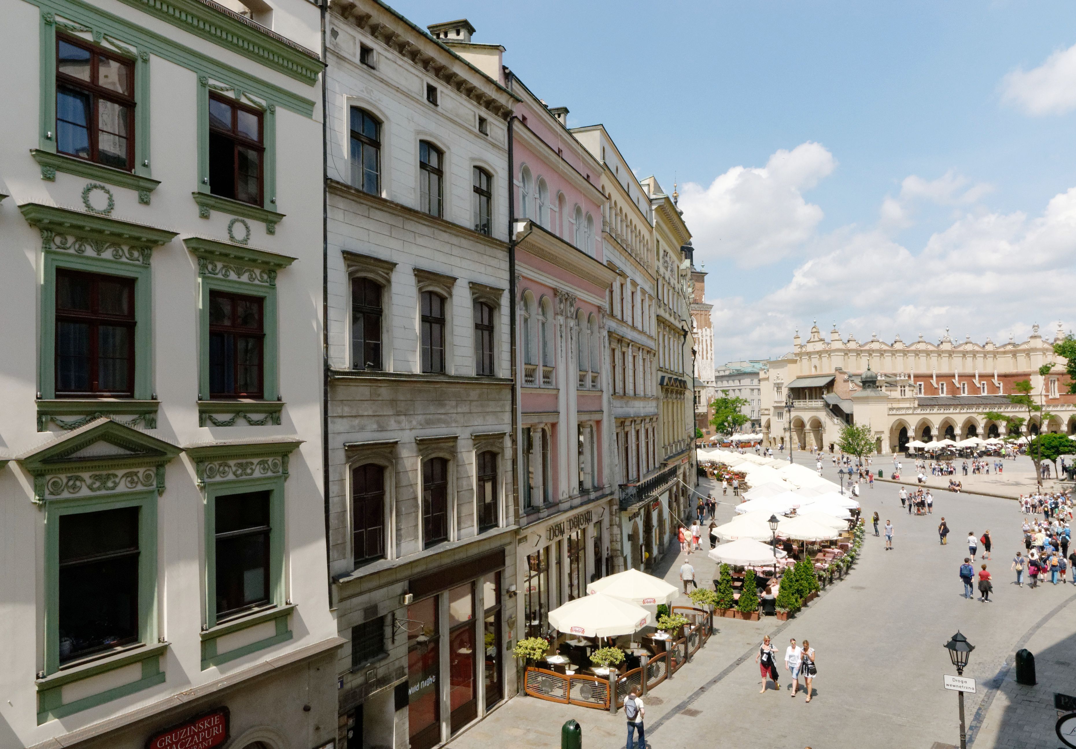 Eine historische europäische Straße mit traditioneller Architektur, Straßencafés und einem öffentlichen Platz.