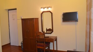Una habitación con un armario de madera, un escritorio con silla, un espejo y una televisión.