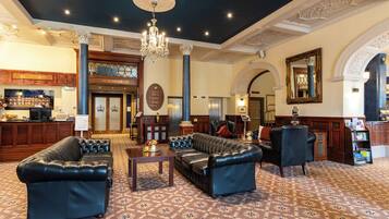 A lobby with leather sofas, a reception desk, a chandelier, and a bar area.