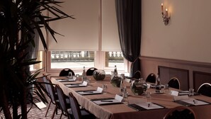 A dining table set for a meal with chairs, a vase, and a bottle of water. - Crown Hotel Harrogate (Harrogate)