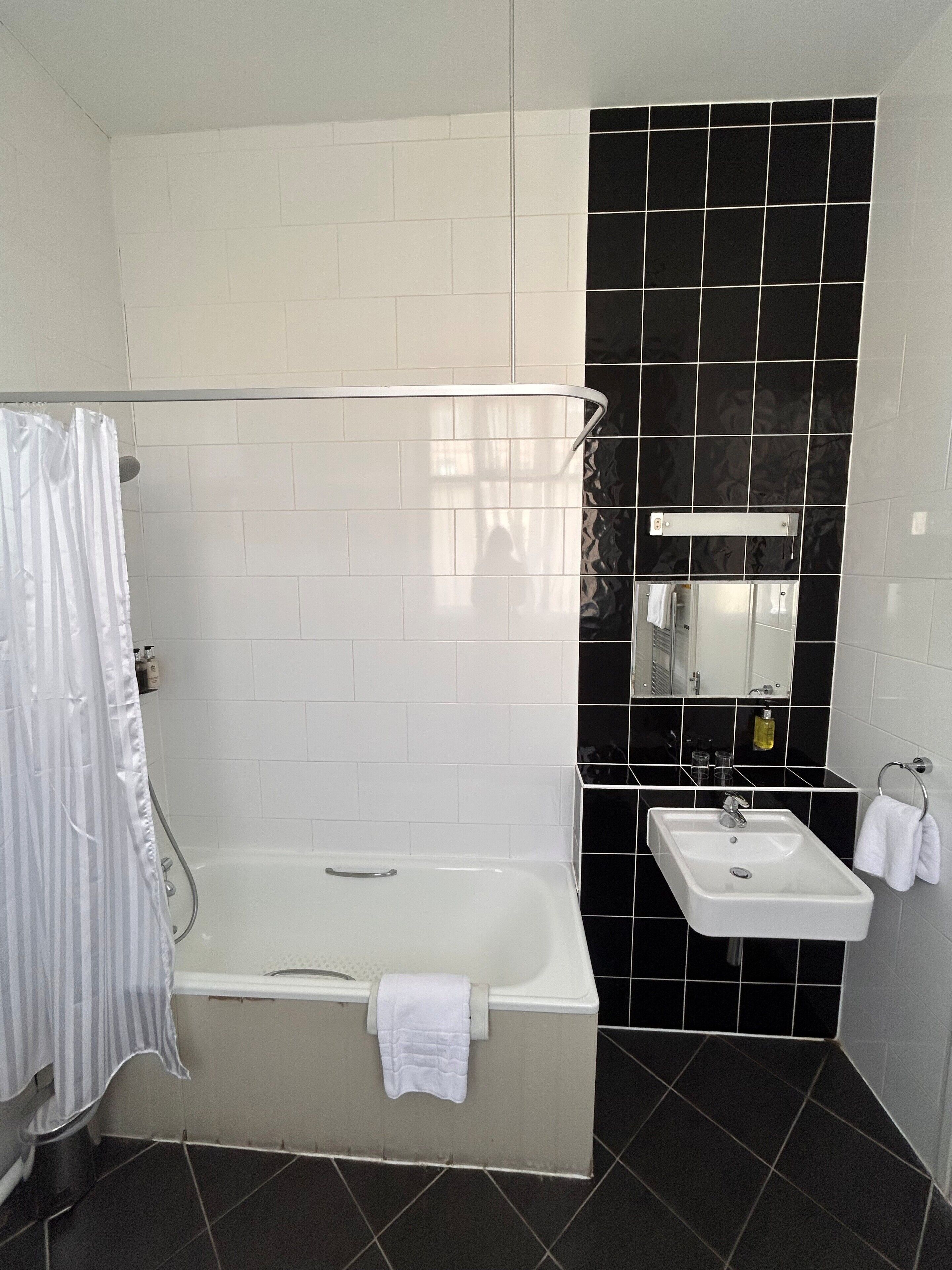 A bathroom with a bathtub, a sink, and a mirror.