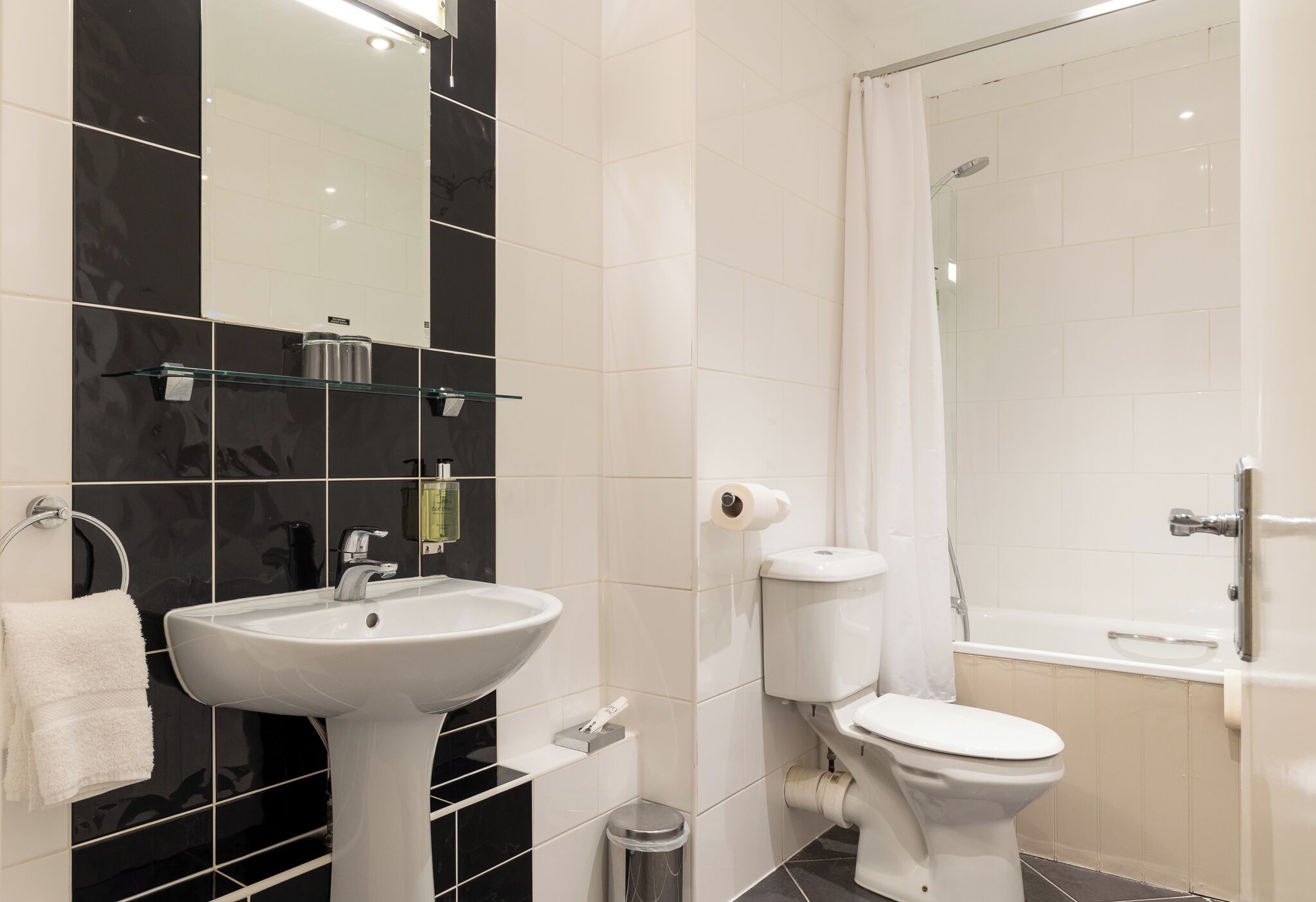 A modern bathroom with a white sink, toilet, and bathtub.
