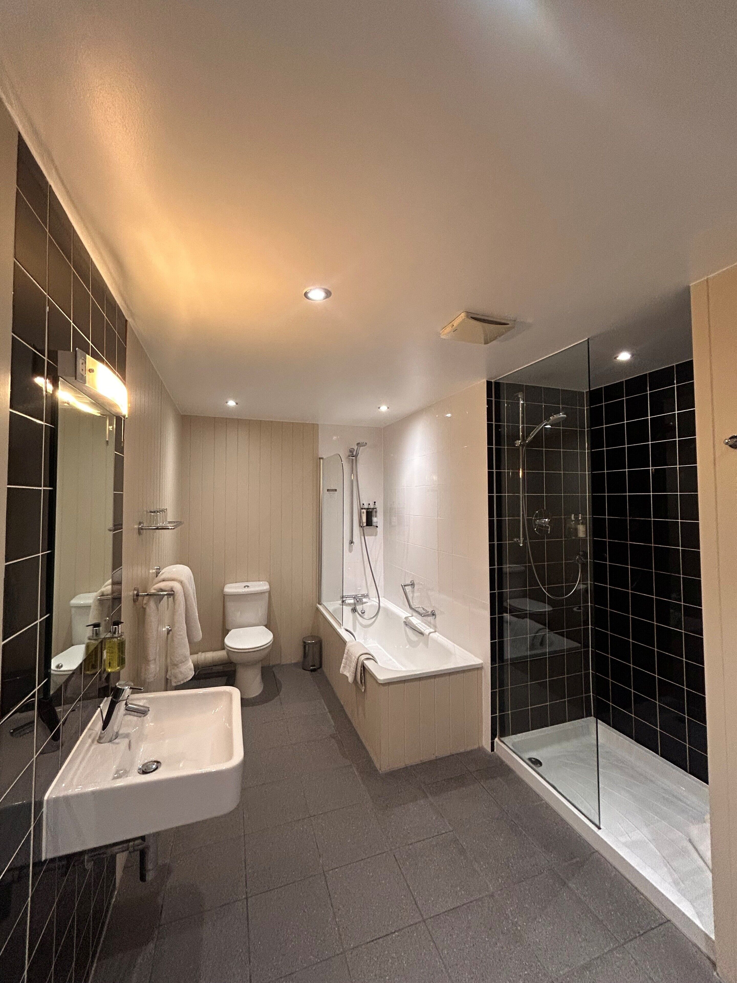 Une salle de bain moderne avec une douche à parois de verre, un lavabo blanc et des toilettes.