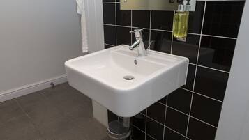 A bathroom with a white sink, black tiled walls, and a mirror above the sink.