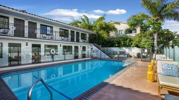 A hotel with a swimming pool, outdoor seating, and a staircase leading to the upper floors.