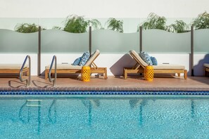 A poolside area with lounge chairs and a pool.