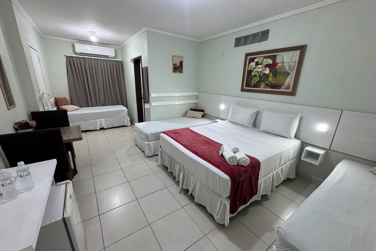 A hotel room with two beds, a dining table, and a small kitchen area.