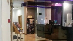 A modern lobby with a reception desk, a glass partition, and a display stand with items. - Hostal Buenos Aires (Madrid)
