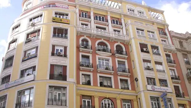 A multi-story building with balconies and signage for businesses. - Hostal Buenos Aires (Madrid)