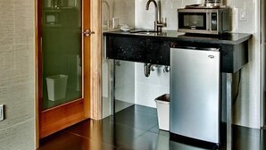 A modern kitchen with a black countertop, stainless steel appliances, and a wooden door.