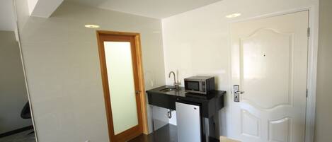 A compact kitchen with a microwave, sink, and small refrigerator.