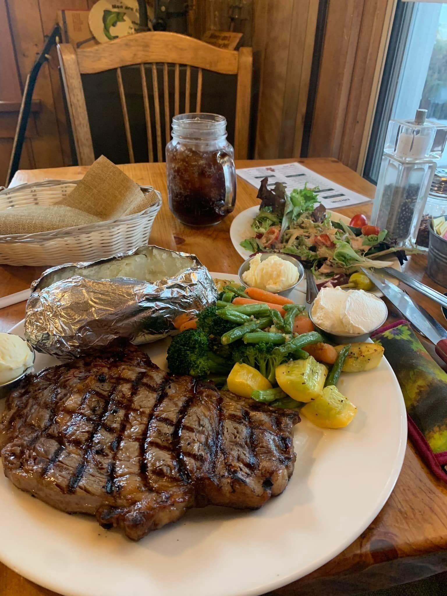 Une assiette comprenant un steak grillé, des légumes rôtis et une salade en accompagnement.