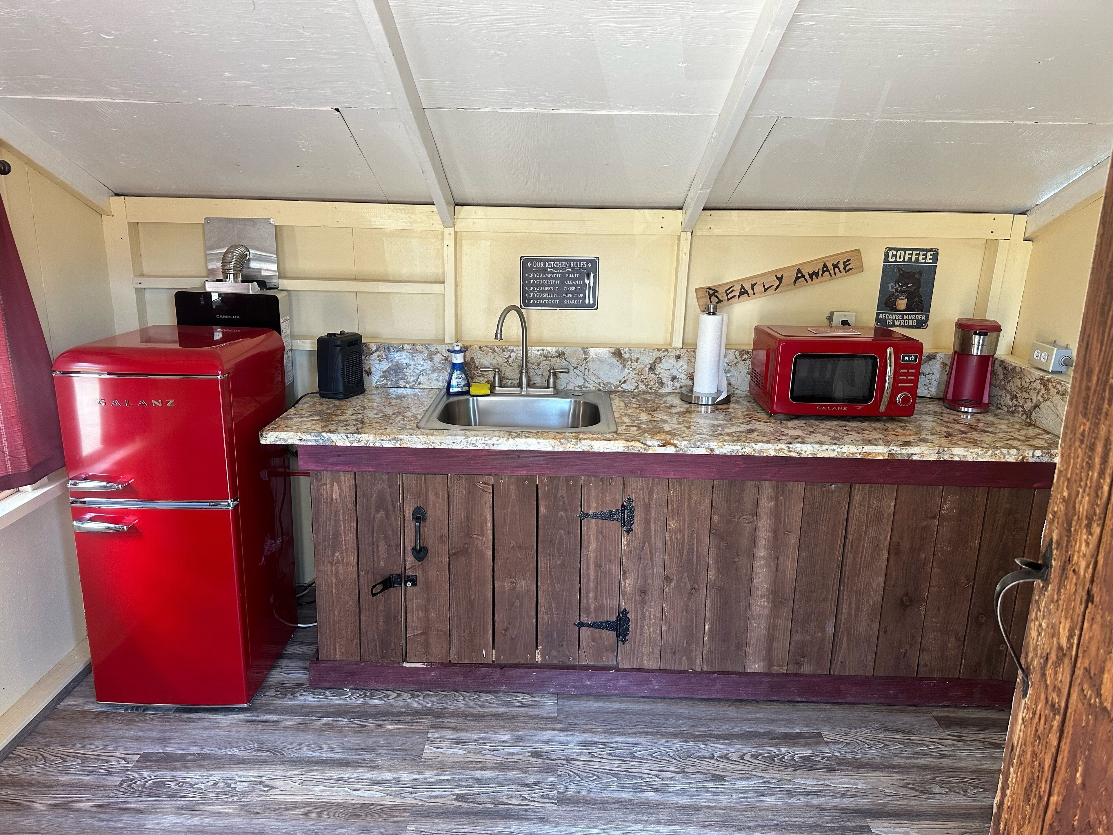 A compact kitchen with a red Galanz refrigerator, a sink, a coffee machine, and a microwave.