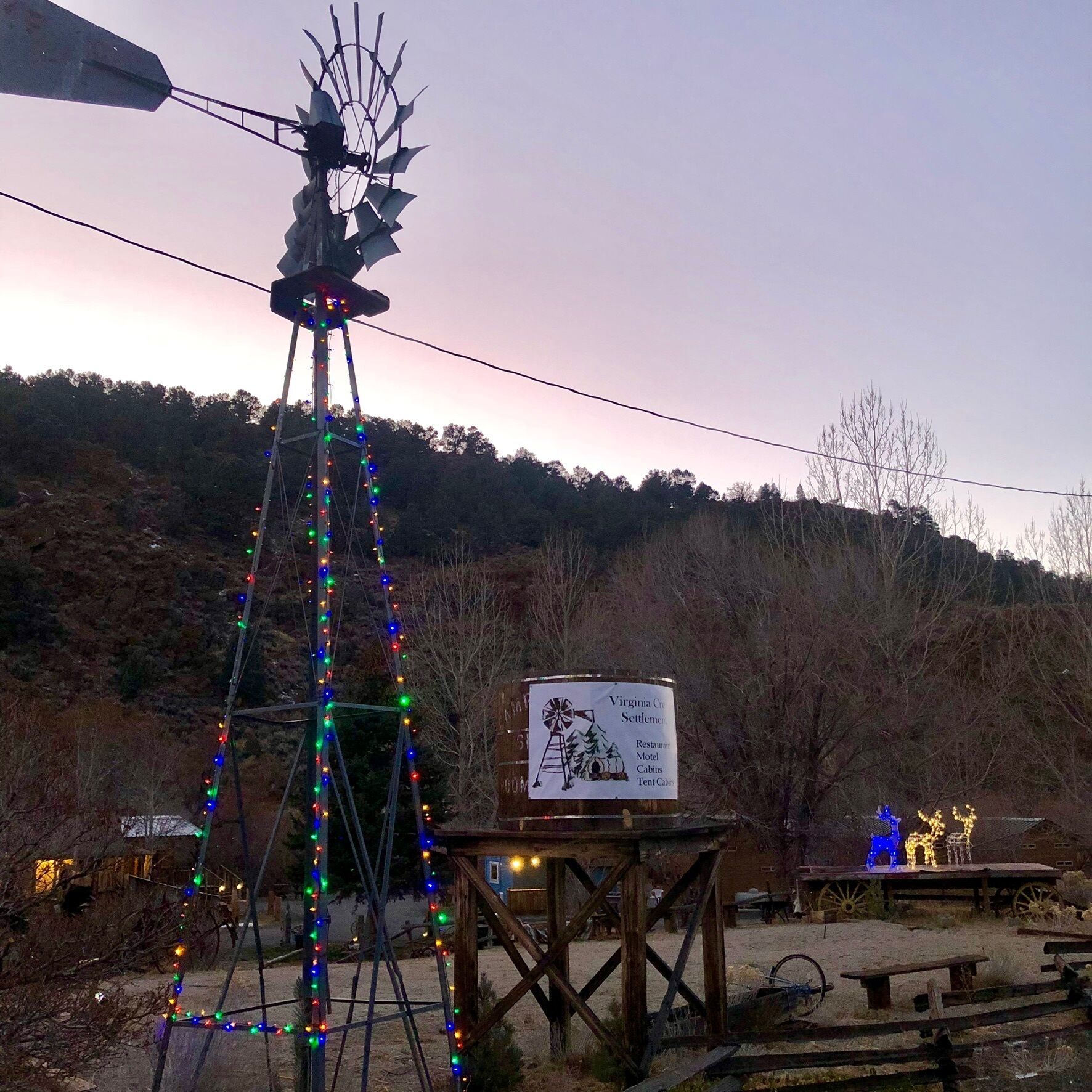 Eine Windmühle mit bunten Lichtern, ein Schild für Virginia Creek Settlement und rustikale Gartenmöbel.